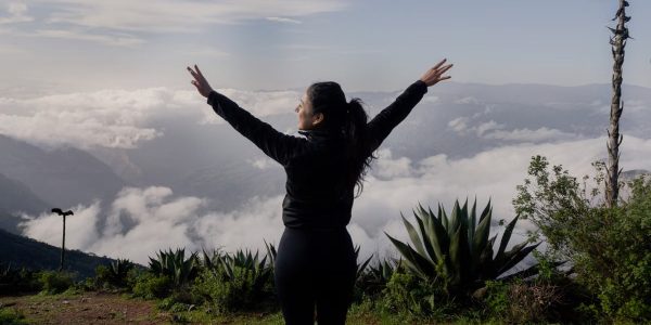 A woman with arms raised enjoying a scenic mountain view in Pinal de Amoles, Mexico.